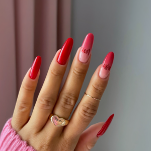 Close-up of beautifully designed Valentine’s Day nails featuring red nails and red airbrush tips with red heart design