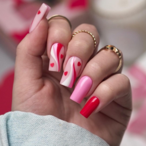 Valentine's nail featuring mixture of red, white and pink nails with a few red heart design