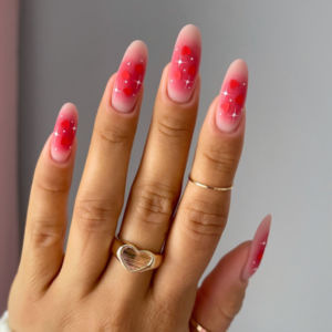 Close-up of beautifully designed Valentine’s Day nails featuring pink airbrush in the middle with white hearts