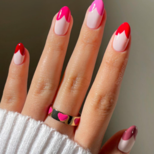 Close-up of beautifully designed Valentine’s Day nails featuring different shades of pink and red french tips in the form heart