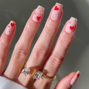 Close-up of beautifully designed Valentine’s Day nails featuring red heart and little diamonds