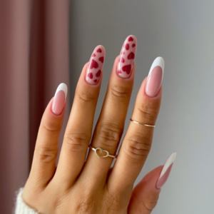 Close-up of beautifully designed Valentine’s Day nails featuring white french tips and red hearts designs