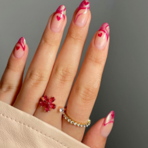 Close-up of beautifully designed Valentine’s Day nails featuring pink anf red lines with red heart design