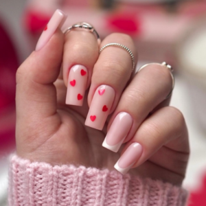 Close-up of beautifully designed Valentine’s Day nails featuring white french tips and small red hearts