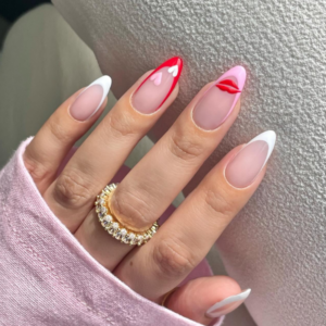 Close-up of beautifully designed Valentine’s Day nails featuring a mix of red, white and pink ed french tips with a kiss design on the middle finger and hearts on the ring finger