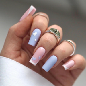 Close-up of beautifully designed Valentine’s Day nails featuring blue nails with white heart designs and white french tips