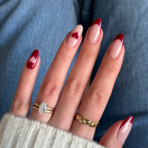 Close-up of beautifully designed Valentine’s Day nails featuring dark red french tips and red heart on the ring finger