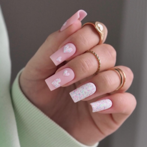 Close-up of beautifully designed nails featuring a mixture of pink and white nails with white hearts on the pink nails