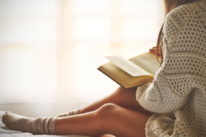 Cozy reading nook with a book, warm blanket, and a cup of tea, perfect for solo relaxation and self-love.