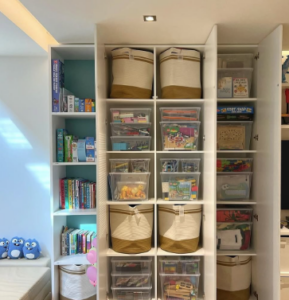 A colorful toy closet with shelves, bins, and hooks, decorated with fun wallpaper to create a special space for toys.