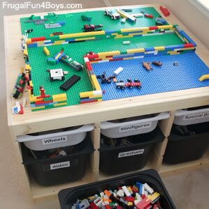 A colorful DIY Lego table featuring built-in storage bins underneath and glued-on Lego baseplates on the surface, creating a dedicated play zone for kids to build and organize their Lego creations easily.