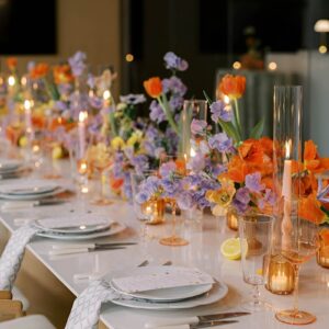 A refined Easter table with deep jewel-toned tablecloth, fine china, crystal glassware, and candles creating a warm ambiance.