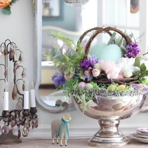 Easter basket centerpiece with pastel eggs, fresh flowers, moss, and a cute bunny figurine, enhanced with fairy lights.