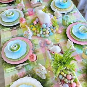 A beautifully set Easter table with pastel-colored plates, gold cutlery, and a floral centerpiece of fresh tulips and daffodils.