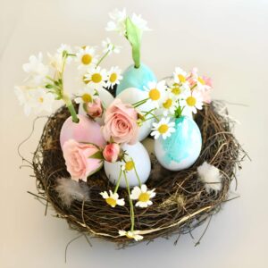 Creative Easter centerpiece featuring cracked eggshells used as tiny vases, filled with daisies, baby’s breath, and mini roses in an egg carton.