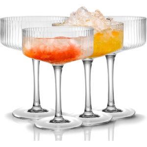 A set of colorful, retro-style coupe glasses filled with cocktails. Great Housewarming gift