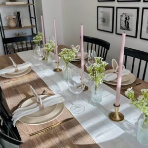 A sleek and modern Easter table with neutral-toned dinnerware, linen napkins, white candles, and a simple floral centerpiece.