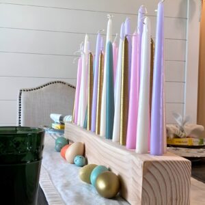 Elegant Easter centerpiece with pastel-colored pillar candles on a rustic tray, surrounded by faux moss, speckled eggs, and greenery.