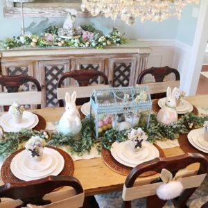 A cozy Easter table with a wooden table setting, burlap runner, mason jar vases filled with wildflowers, and ceramic bunnies.