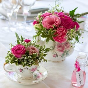 A charming Easter centerpiece featuring vintage teacups filled with fresh flowers, moss, and tiny decorative eggs, stacked on a tiered cake stand.