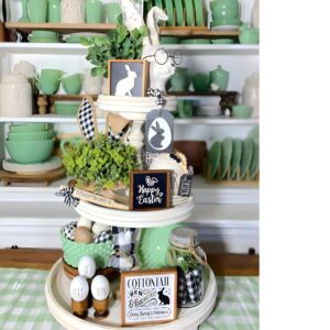 A festive tiered Easter centerpiece with mini nests, pastel eggs, ceramic bunnies, fresh flowers, and decorative carrots on a three-tiered tray.