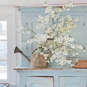 A rustic Easter centerpiece using a small metal watering can filled with tulips, daisies, and daffodils, tied with a pastel ribbon.